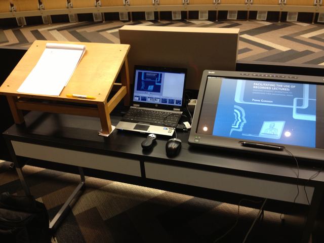 Lectern with a laptop and a screen showing the title slide.