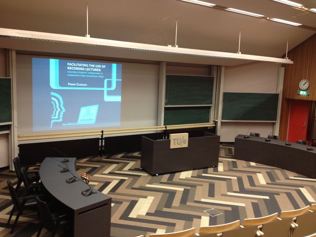Lecture hall with the title slide on the projection screen and the committee table in front.