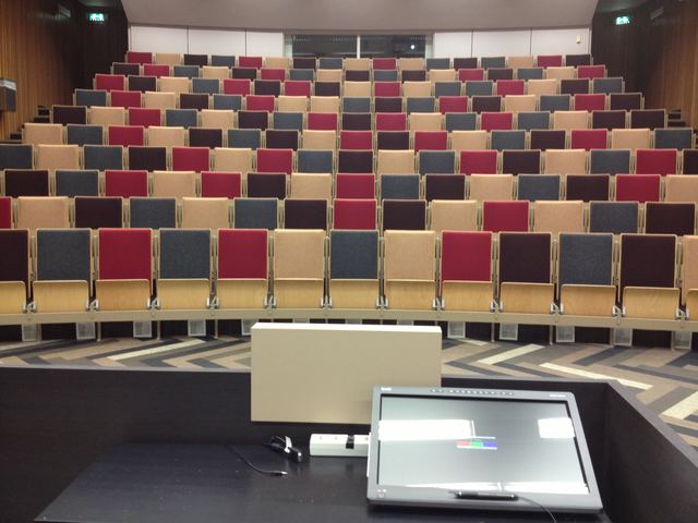 Rows of red, grey and wooden seats in the empty auditorium.