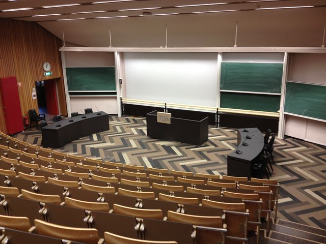 The auditorium seen from the side, with whiteboards and the committee tables.